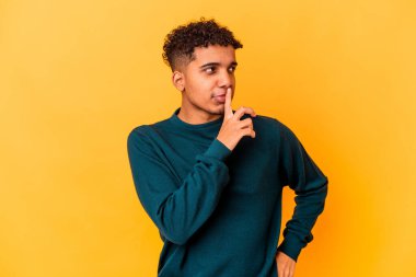 Genç Afro-Amerikan kıvırcık adamı, mor renkte izole edilmiş, kuşkulu ve kuşkulu bir ifadeyle yana bakıyor..