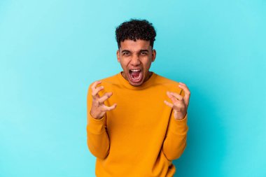 Genç Afro-Amerikalı kıvırcık adam mavi üzerine izole edilmiş gergin elleriyle çığlık atıyor..