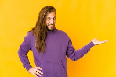 Uzun saçlı genç adam avucunun içinde fotokopi odası gösteriyor ve belinde bir el daha tutuyor..