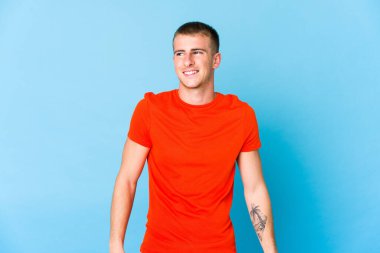 Genç beyaz yakışıklı adam gülüyor ve gözlerini kapıyor, rahatlamış ve mutlu hissediyor..