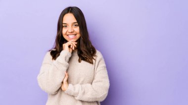 Genç, melez, yalnız, mutlu ve kendinden emin, çenesine elleriyle dokunan bir kadın..