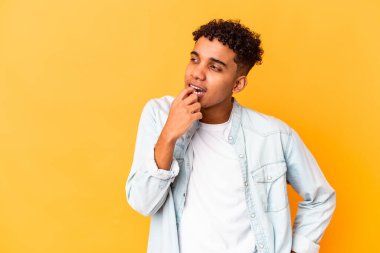 Genç Afro-Amerikalı kıvırcık adam, mor üzerine izole edilmiş, rahat bir şekilde fotokopi odasına bakan bir şey düşünüyor..