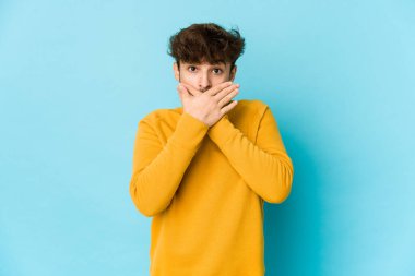 Mavi arka plandaki genç Arap adam elleriyle ağzını kapatırken şok oldu..