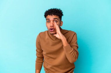 Genç Afro-Amerikalı kıvırcık adam mavi üzerine izole edilmiş gizli bir sıcak fren haberi veriyor ve yana bakıyor.