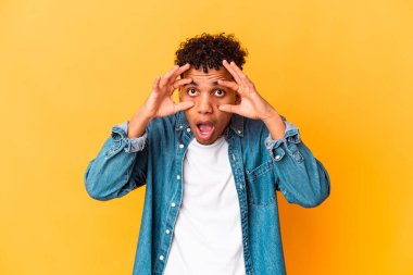 Genç Afro-Amerikalı kıvırcık adam, mor üzerine izole edilmiş, gözlerini açık tutarak bir başarı fırsatı arıyor..