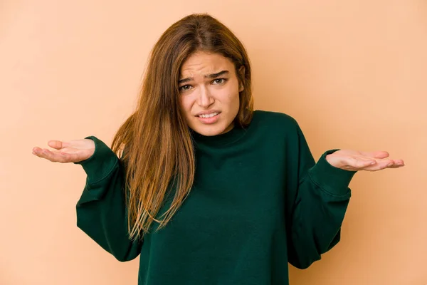 Young skinny caucasian teenager girl confused and doubtful shrugging shoulders to hold a copy space.