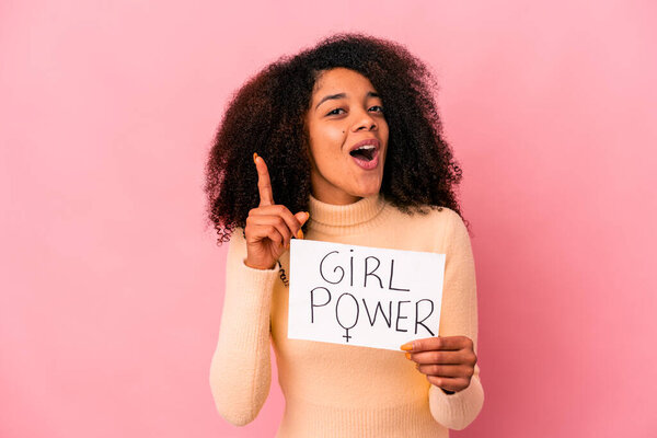 Young african american curly woman holding a girl power message on a placard having an idea, inspiration concept.