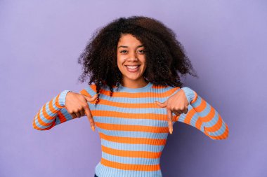 Genç Afro-Amerikalı kıvırcık kadın mor arka planda izole edilmiş parmakları aşağıda, pozitif bir his..