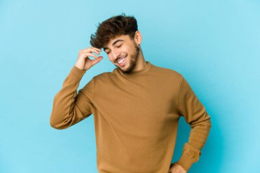 Mavi arka plandaki genç Arap adam çok gülerdi. Mutluluk kavramı.