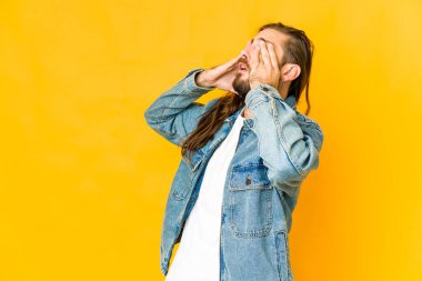 Uzun saçlı genç adam korkuyla gözlerini kapatıyor..