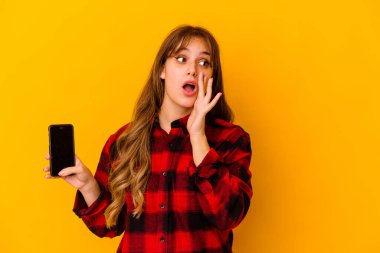Sarı arka planda telefon tutan beyaz bir kadın gizli bir sıcak fren haberi veriyor ve yan bakıyor.