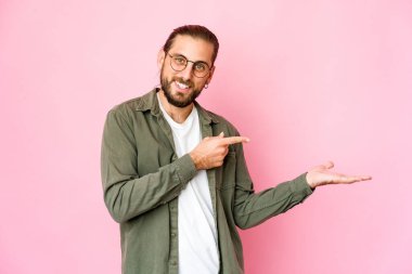 Uzun saçlı genç adam, elinde bir fotokopi odası tutarken heyecanlı görünüyor..