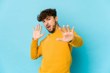 Mavi arka plandaki genç Arap, yakın bir tehlike nedeniyle şoka uğruyor.