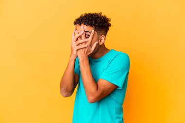 Genç Afro-Amerikalı kıvırcık adam, mor bir ışıkta izole edilmiş parmaklarıyla korkmuş ve gergin.