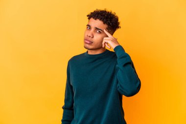 Genç Afro-Amerikan kıvırcık adamı, mor bir şakakta izole edilmiş, parmağıyla işaret eden, düşünen, bir göreve odaklanmış..