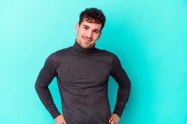 Mavi arka planda izole edilmiş genç beyaz adam mutlu, güler yüzlü ve neşeli.