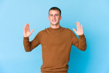 Kafkasyalı yakışıklı genç adam işaret parmaklarıyla küçük bir şey tutuyor, gülümsüyor ve kendinden emin..