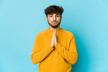 Mavi arka planda dua eden, kendini adamış dindar, ilahi ilhamı arayan genç bir Arap..