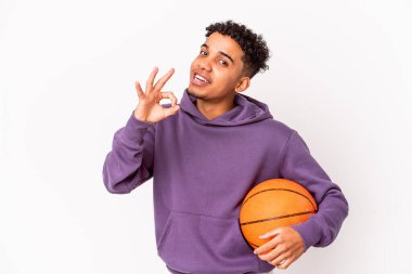 Genç Afro-Amerikalı kıvırcık adam yalnız başına basketbol oynuyor. Neşeli ve kendinden emin..