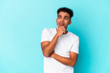 Genç Afro-Amerikan kıvırcık adamı mavi düşüncelere dalıp yukarı bakıyor, yansıtıyor, düşünüyor, bir fantezi kuruyor..