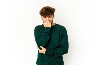 Beyaz arka planda genç bir Arap tırnaklarını yiyor, gergin ve çok endişeli..