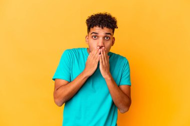 Genç Afro-Amerikalı kıvırcık adam mor renkte izole edilmiş ağzı elleriyle kapatıyor..