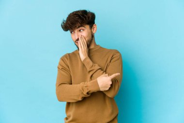 Mavi arka plandaki genç Arap bir dedikodu söylüyor, bir haber sunuyor..