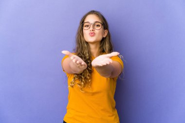 Beyaz tenli tatlı bir kadın dudaklarını katlıyor ve hava öpücüğü vermek için avuç içi tutuyor..