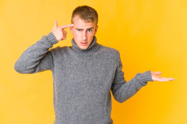 Genç, beyaz, yakışıklı bir adam elinde bir ürün tutuyor..