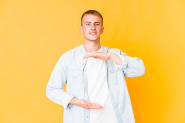 Kafkasyalı yakışıklı bir adam iki eliyle bir şey tutuyor, ürün sunumu..