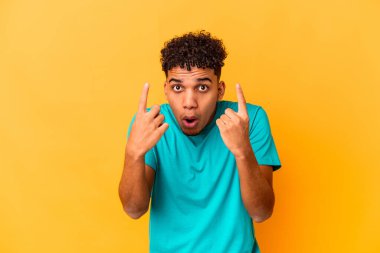 Genç Afro-Amerikalı kıvırcık adam mor renkte, ağzı açık, üst tarafı işaret ediyor..