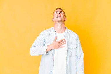 Beyaz tenli yakışıklı adam elini göğsüne koyup kahkahalar atıyor..