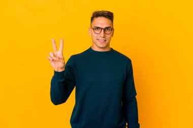 Genç, yakışıklı, beyaz bir adam izole edilmiş zafer işareti gösteriyor ve gülümsüyor..