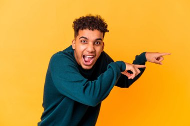 Genç Afro-Amerikan kıvırcık adamı, mor renkte izole edilmiş, işaret parmağıyla işaret ediyor..