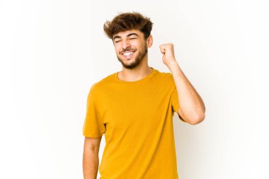 Beyaz arka plandaki genç Arap adam zaferi, tutkuyu ve coşkuyu, mutlu ifadeyi kutluyor..