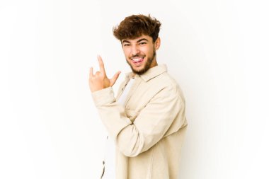 Beyaz arka planda genç bir Arap, parmaklarıyla kaya hareketi gösteriyor.