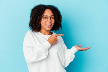 Genç Afro-Amerikan melez kadın kendini soyutlamış gülümsüyor ve boş uzayda bir şeyler gösteriyor..