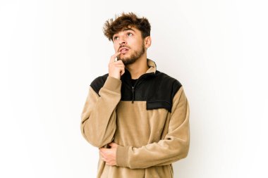 Beyaz arka planda genç bir Arap şüpheli ve şüpheci bir ifadeyle yana bakıyor..