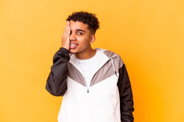 Genç Afro-Amerikan kıvırcık adamı, mor renkte izole edilmiş, yüzünün yarısını palmiye ile kaplayarak eğleniyor..