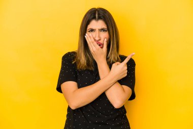 Sarı arka planda izole edilmiş genç Hintli kadın yan tarafı gösteriyor.