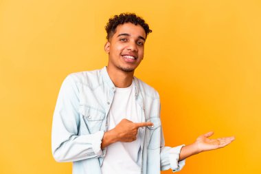 Genç Afro-Amerikalı kıvırcık adam, mor renkte izole edilmiş. Elinde palmiye ağacının bir kopyası var..