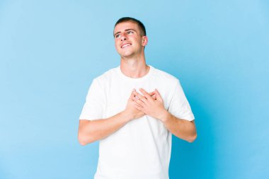 Genç, beyaz, yakışıklı bir adam gülüyor. Elini yüreğine koyuyor. Mutluluk kavramı..