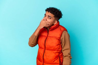 Genç Afro-Amerikalı kıvırcık adam mavi üzerine izole edilmiş korkmuş ve korkmuş.