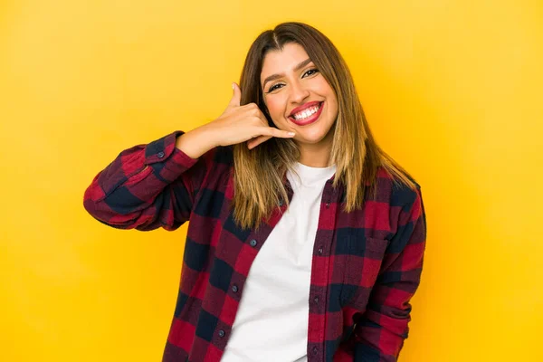 stock image Young indian woman isolated on yellow background showing a mobile phone call gesture with fingers.