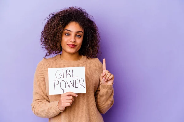 一个年轻的非洲裔美国女人拿着一个紫色背景的女孩权力标牌 上面用手指显示第一位 — 图库照片