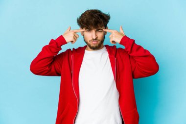 Mavi arka plandaki genç Arap adam bir göreve odaklanmış, işaret parmaklarını işaret ediyor..