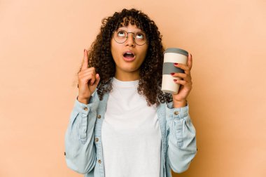 Genç Afro-Amerikan Afro kadın elinde açık ağızlı, üst tarafı gösteren bir kahve tutuyor..