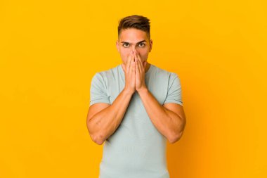 Genç, yakışıklı, beyaz bir adam izole edilmiş. Ağzını elleriyle kapatmış..
