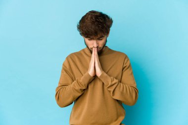 Mavi arka planda dua eden, kendini adamış dindar, ilahi ilhamı arayan genç bir Arap..