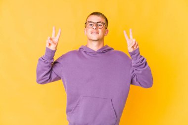 Kafkasyalı yakışıklı genç adam zafer işareti gösteriyor ve gülümsüyor..